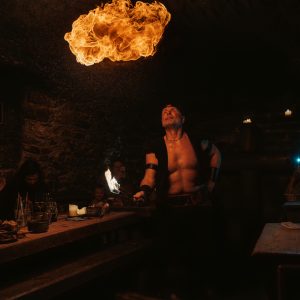 Fire performer blowing a ball of flame inside a subterranean stone tavern in Pragu