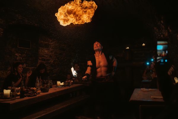 Fire performer blowing a ball of flame inside a subterranean stone tavern in Pragu
