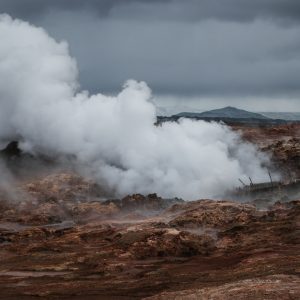 Steam rising from a geothermal landscape beneath dark clouds in Iceland