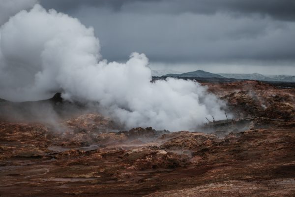 Steam rising from a geothermal landscape beneath dark clouds in Iceland