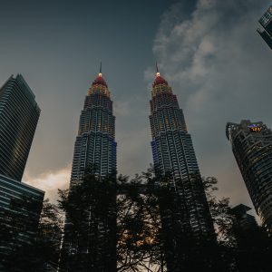 Low angle view looking up at the illuminated Petronas Twin Towers framed by surrounding skyscrapers in Kuala Lumpur at twilight
