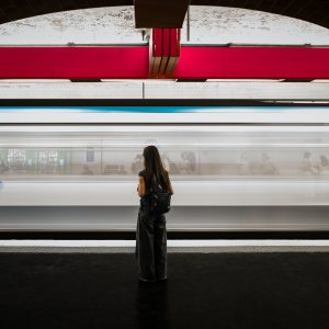 Woman standing on a Paris Metro platform as a train passes in motion blur