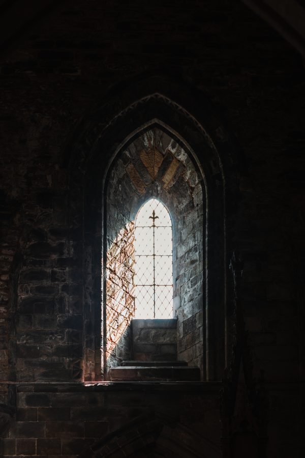 Gothic arched window illuminated by daylight inside St Davids Cathedral, Wales