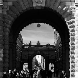 Black and white street photograph of an archway in Stockholm with people walking through
