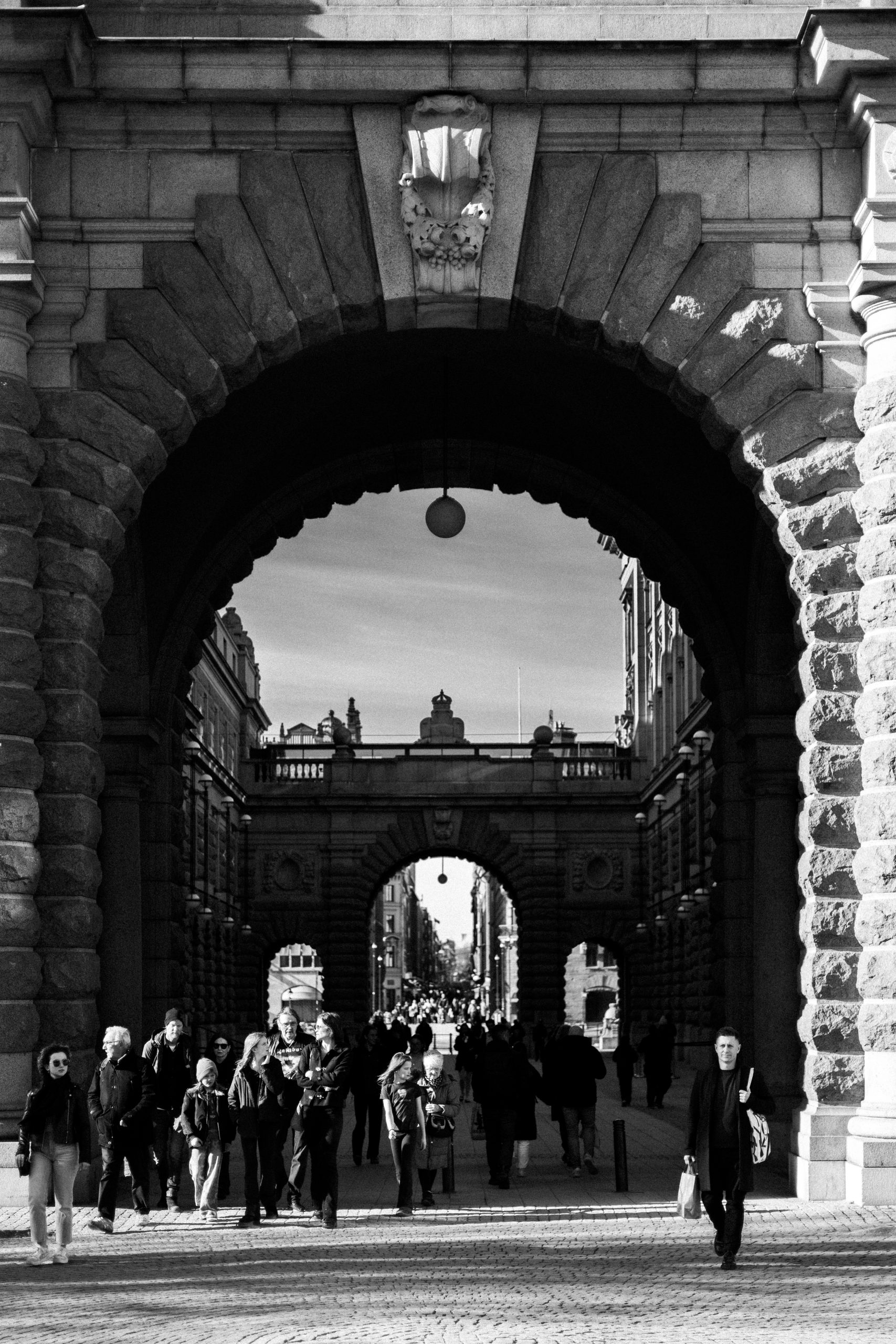 Black and white street photograph of an archway in Stockholm with people walking through